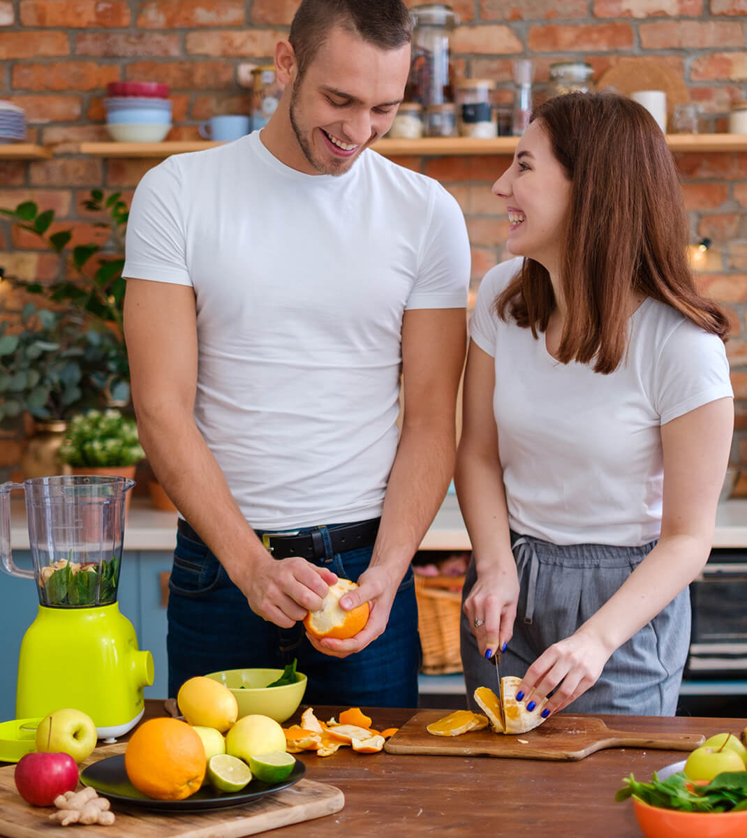 Pareja cocinando y haciendo un zumo con frutas