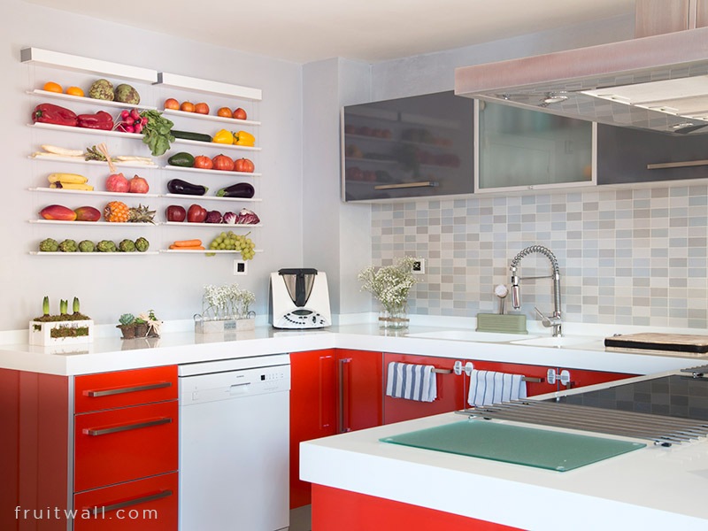 Fruteros de pared colgantes Fruitwall, colgados dos uno al lado del otro en una cocina grande decorada en rojo y blanco, estan llenos de frutas y verduras,